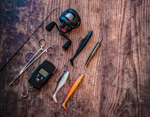 Flat lay of bass lure fishing tackle on a plain wooden background