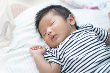 Adorable Asian sleeping, tiny infant healthy sleep with warm wool white blanket at home, baby health care concept.