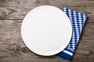 White ceramic tray on a wooden table with a Bavarian napkin, top view. Food background