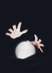 Man's hands over a magic crystal ball on a black background. Session for predicting the future.