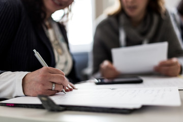 Zwei Frauen sitzen in einer Besprechung und machen Notizen