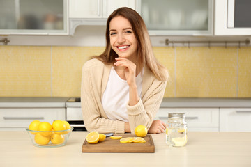 Young woman making lemon water in kitchen