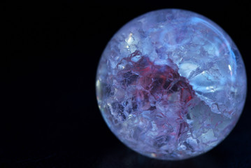 Glowing crystal ball with cracks inside on a dark background. The process of predicting the future