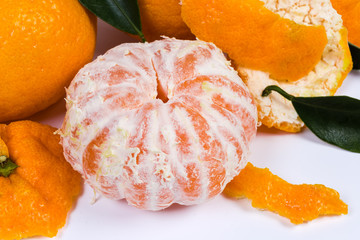 Peeled mandarin orange among the peel and other fruits closeup
