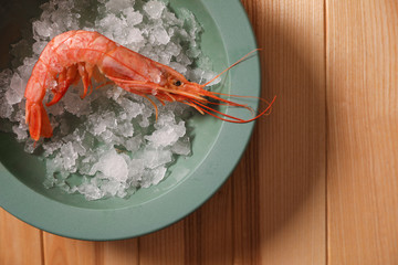Fresh royal shrimp with ice on wooden table, top view