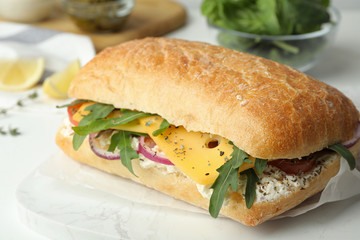 Delicious sandwich with fresh vegetables and cheese on white table, closeup