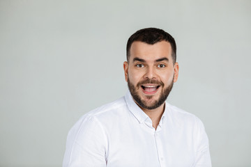 Fototapeta premium Portrait of young surprised handsome bearded man with shocked facial expression on gray background