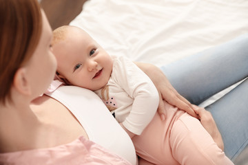 Young woman with her little baby resting after breast feeding on bed, above view