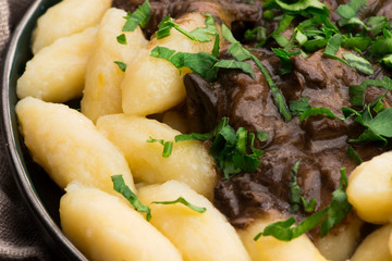 Freshly cooked, Polish traditional potato dumplings serving with mushroom sauce and fresh parsley