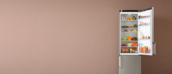Open fridge full of food on color background with space for text