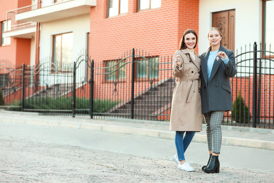 Young Lesbian Couple With Keys Near Their New House