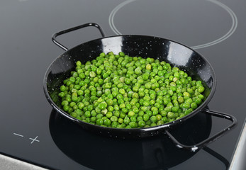 Cooking frozen sweet peas on induction stove. Vegetable preservation