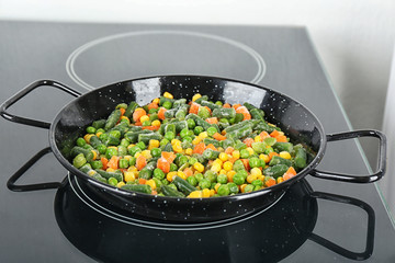 Cooking tasty frozen vegetable mix on induction stove