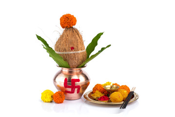 Copper Kalash with coconut and mango leaf and pooja thali with diya, kumkum and sweets with floral...