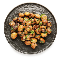 Plate with tasty cooked mushrooms on white background