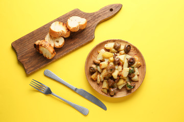 Plate with tasty cooked mushrooms and potato on color background