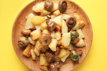 Plate with tasty cooked mushrooms and potato on color background