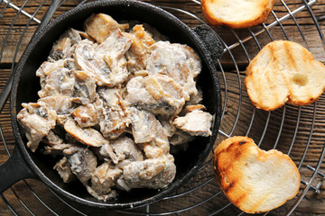 Frying pan with tasty cooked mushrooms on table