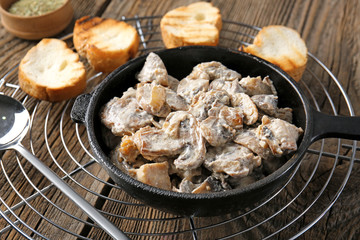 Frying pan with tasty cooked mushrooms on table