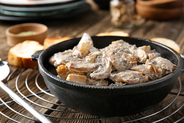 Frying pan with tasty cooked mushrooms on table