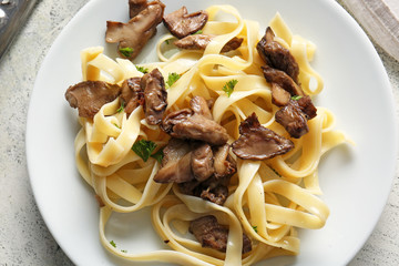 Plate with tasty cooked mushrooms and pasta on table