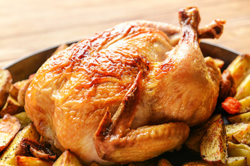 Dish with baked chicken and potato on table, closeup