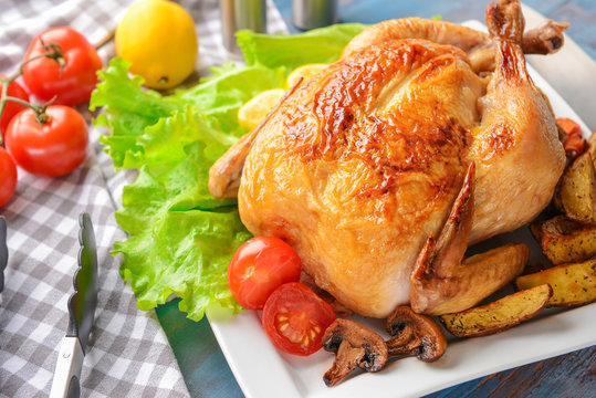 Plate with baked chicken and potato on table