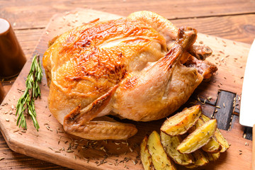 Baked chicken and potato on wooden board