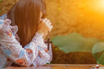 The girl holds the cross in her hand and shows a symbol to pray for the blessing of God with hope...
