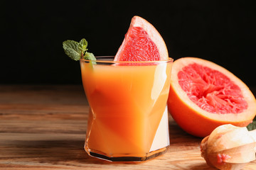 Glass of fresh juice and grapefruit on wooden background