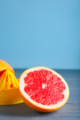 Fresh cut grapefruit and juicer on wooden table