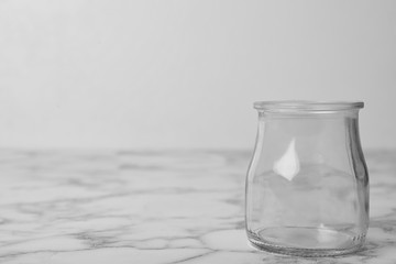 Empty glass jar on white marble table, space for text