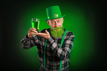 Funny mature man with glass of beer on dark background. St. Patrick's Day celebration