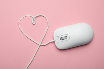 Computer mouse with heart shaped wire on pink background, top view
