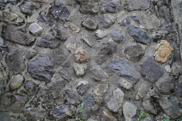 시멘트와 다양한 크기의 돌로 만들어진 오래 된 벽입니다.