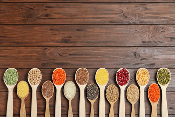 Flat lay composition with different types of legumes and cereals on wooden table, space for text. Organic grains