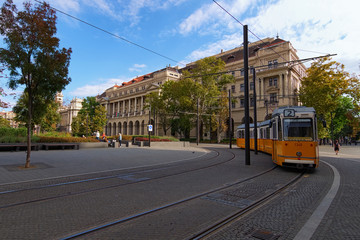 Fototapeta premium Typical yellow vintage tram in Budapest. Line 2 is famous for being the best european line selected by National Geographic. Medieval buildings in the background. Travel and tourism concept. Hungary