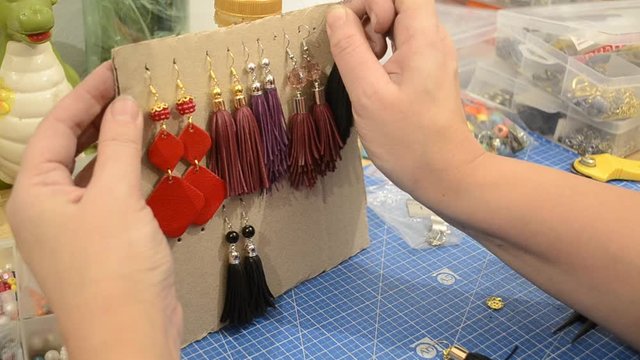 The girl fastens handmade earrings made of genuine leather