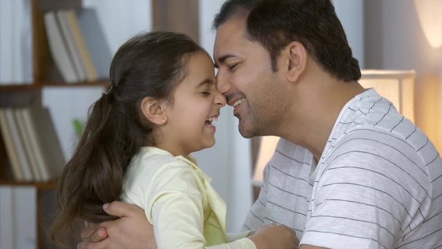 Indian father and daughter bonding - Having good time at home. Family values and bonding in a happy Indian family. Indian Stock Footage of a doting father kissing his young daughter on the forehead...