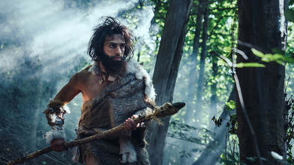 Portrait of Primeval Caveman Wearing Animal Skin and Fur Hunting with a Stone Tipped Spear in the...