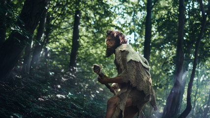 Portrait of Primeval Caveman Wearing Animal Skin and Fur Hunting with a Stone Tipped Spear in the Prehistoric Forest. Prehistoric Neanderthal Hunter Scavenging with Primitive Tools in the Jungle