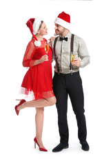 Obraz premium Happy couple in Santa Claus hats and with glasses of champagne on white background