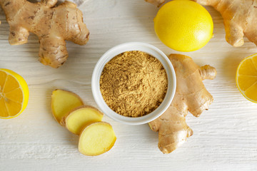 Fresh and ground ginger with lemon on white table