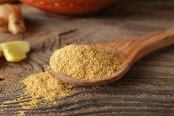 Spoon with ground ginger on wooden table