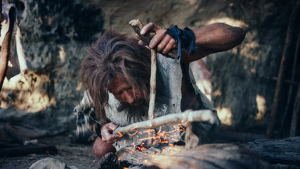 Close-up Shot of a Primeval Caveman Wearing Animal Skin Trying to make Fire with Bow Drill Method....