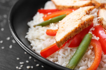 Bowl with tasty rice, chicken and vegetables, closeup