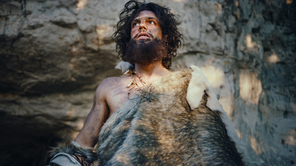 Portrait of Primeval Caveman Wearing Animal Skin Looks Around Forest Defending His Cave and Territory in the Prehistoric Times. Prehistoric Neanderthal or Homo Sapiens Leader