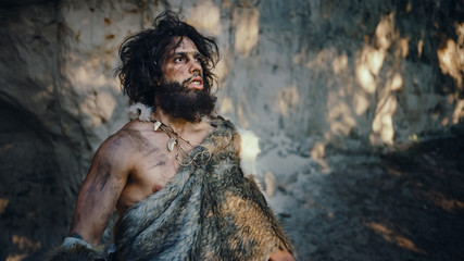 Portrait of Primeval Caveman Wearing Animal Skin Looks Around Forest Defending His Cave and Territory in the Prehistoric Times. Prehistoric Neanderthal or Homo Sapiens Leader