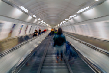 Subway passengers on escalators. Motion blur.