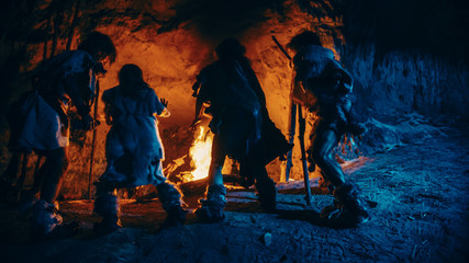 Tribe of Prehistoric Hunter-Gatherers Wearing Animal Skins Dance Around Bonfire Outside of Cave at...